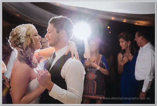Ashley and Payden gaze at each other on the dance floor, backlit by a glowing lamp