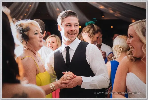 Payden grins dancing with a guest in a yellow dress amid the packed Carilley Estate party