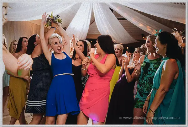 Guests leap and lunge to catch the airborne bouquet, the woman in blue triumphant at Carilley Estate