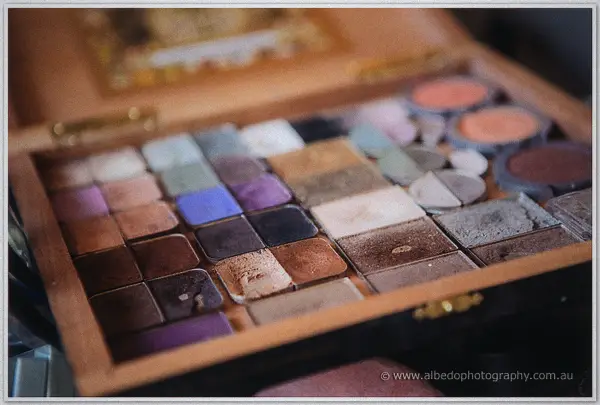 Vintage case of pressed eyeshadow powders in plum, bronze and blue tones catches soft morning light