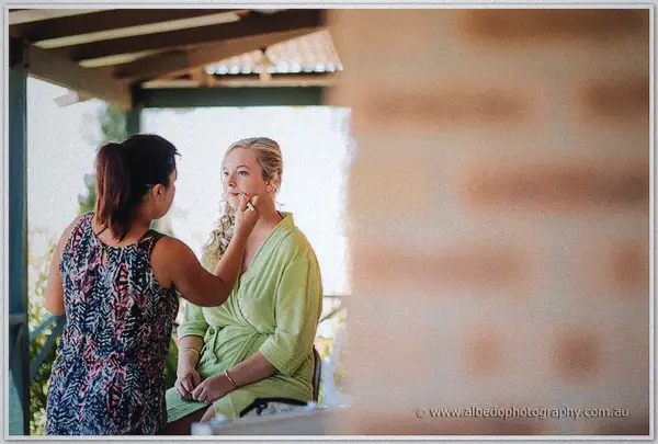 Makeup artist brushes colour onto Tash's eyes as she sits in a green robe on the veranda