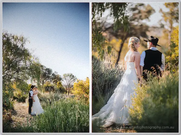 Tash and Gary embrace in a sunlit clearing framed by tall grass and yellow wattle