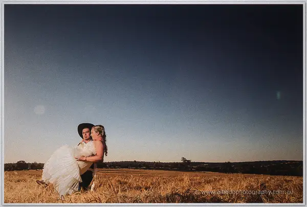 Gary sweeps Tash off her feet in the stubble field beneath a deepening dusk sky