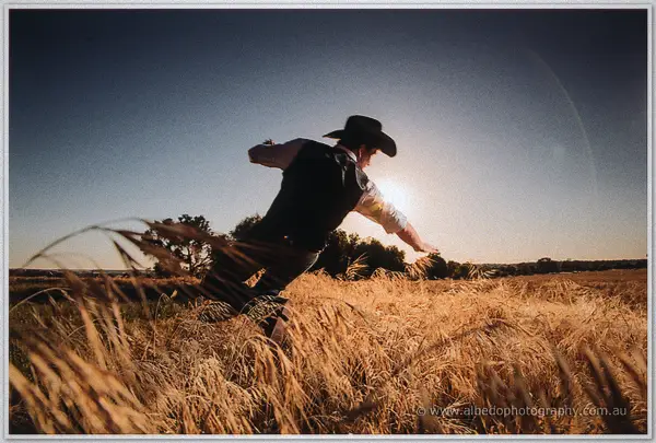 Gary lunges through the backlit oat crop, arms flailing, sun blazing on the horizon
