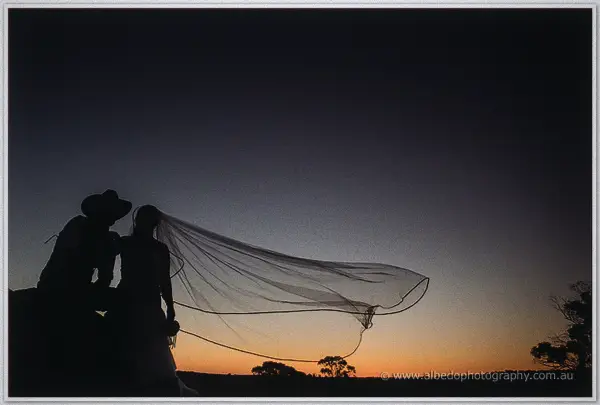 Dusk silhouette of the couple as Tash's veil billows sideways against the fading sky