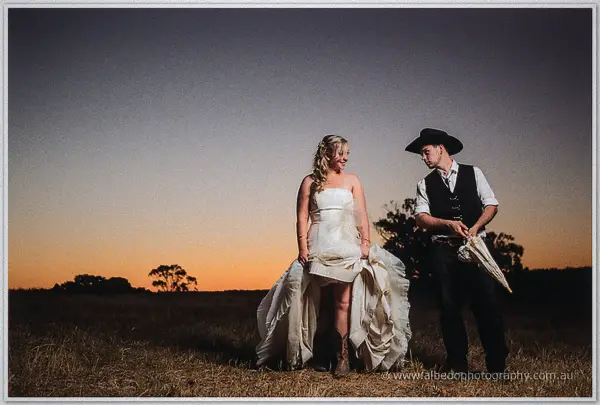 Tash lifts her gown to reveal cowgirl boots while Gary gathers the parasol after dark