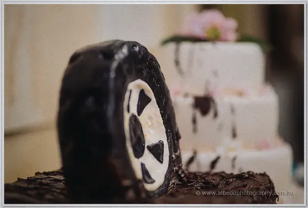 A chocolate 4WD tyre leans against the white tiered wedding cake waiting to be cut