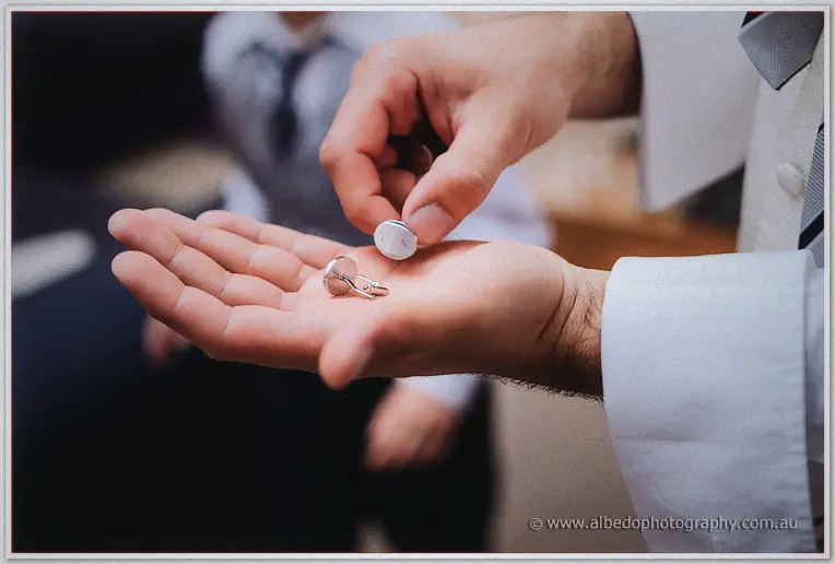 A close-up of hands slipping a polished silver cufflink into an open palm