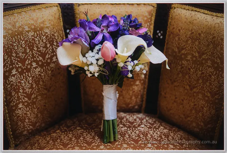 Amanda's bouquet of calla lilies, purple orchids and a pink tulip rests on a gold upholstered chair