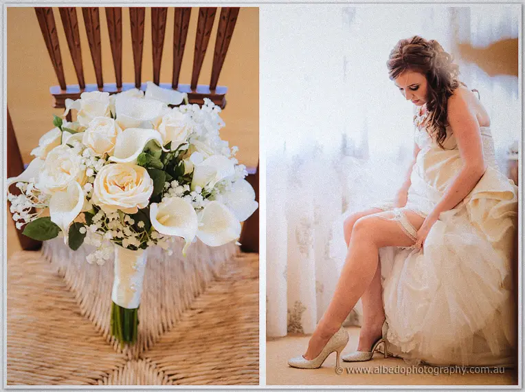 Dusty white bouquet on a rush seat beside Amanda clipping her garter by sheer curtains