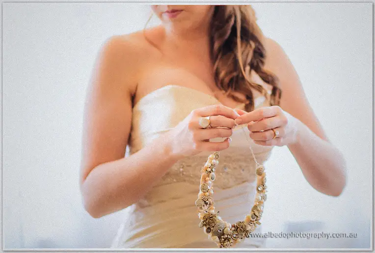 Amanda in her strapless gown holding a vintage pearl and button necklace
