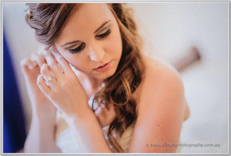 Close-up of Amanda lowering her eyes while touching her pearl earring in soft window light
