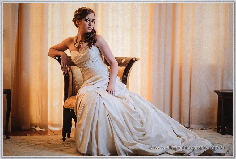 Amanda draped over an antique chair, gown pooled across the rug in golden lamplight
