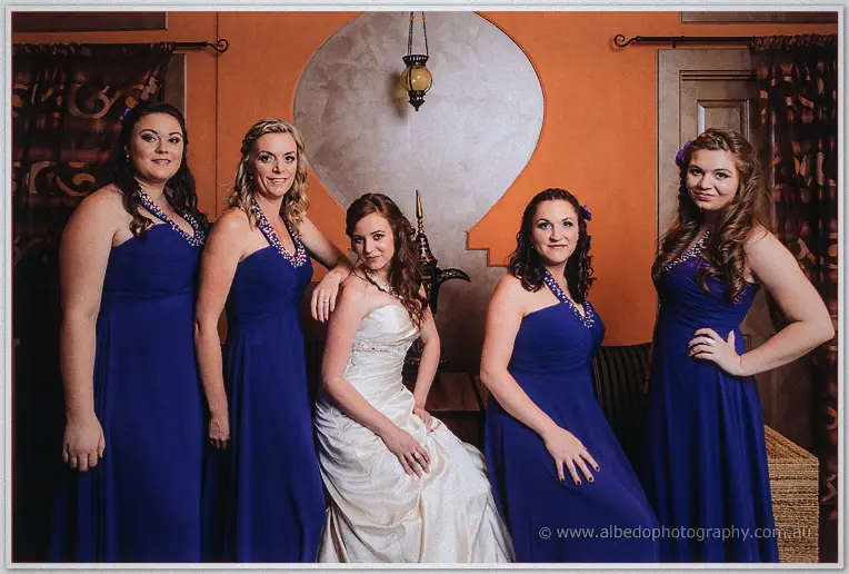 Amanda seated with her four bridesmaids in cobalt gowns against an ochre feature wall
