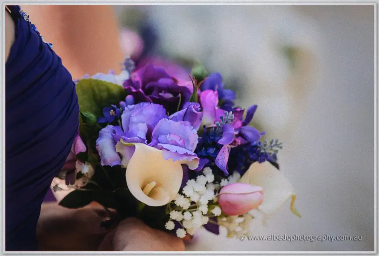 Close-up of purple lisianthus, orchids and a cream calla lily in a bridesmaid's bouquet