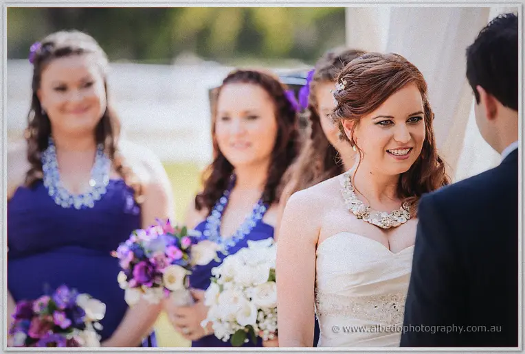 Amanda laughing during vows, bridesmaids in blue soft behind her