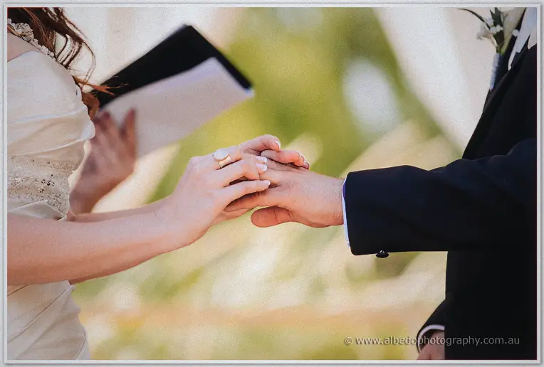 Close-up of Amanda sliding the wedding ring onto Craig's finger