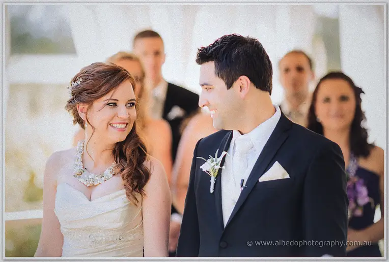 Amanda laughs up at Craig in her strapless lace gown during their sunny garden ceremony