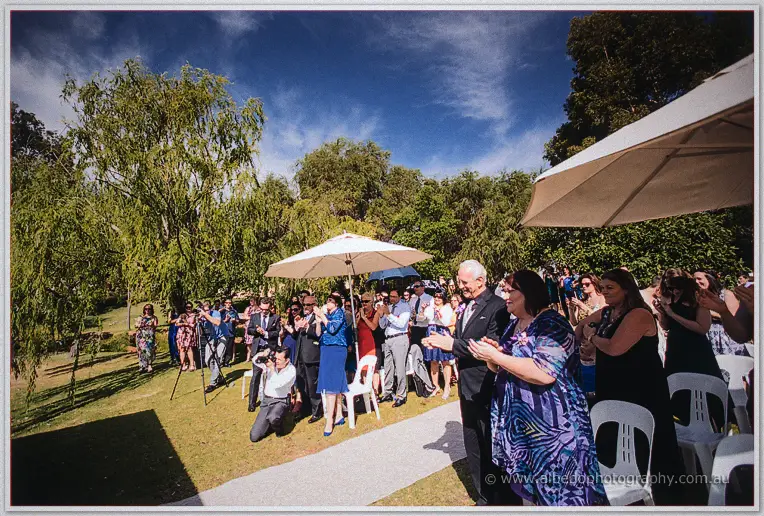 Guests applaud beneath parasols and gum trees after the open-air ceremony at Brookleigh Estate