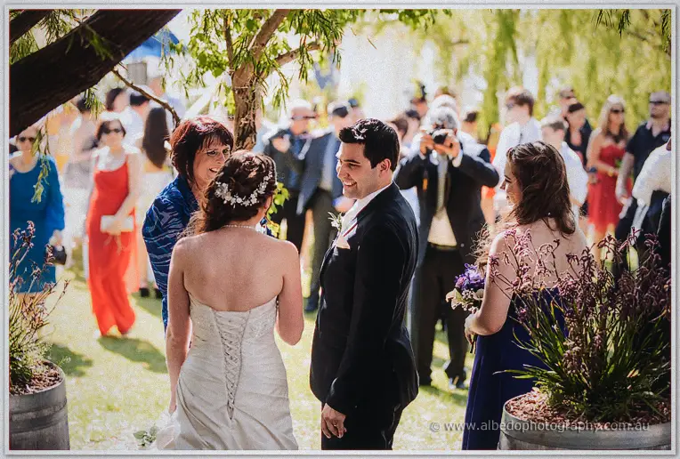 Craig greets his smiling bride under a willow, guests gathered across the Swan Valley lawn