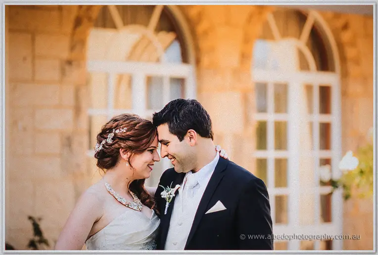Foreheads touching, the couple beam before the limestone facade of Brookleigh's homestead