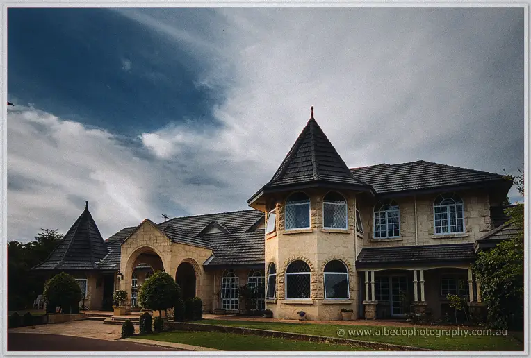 Brookleigh Estate's chateau-style stone facade with conical turrets under drifting grey clouds