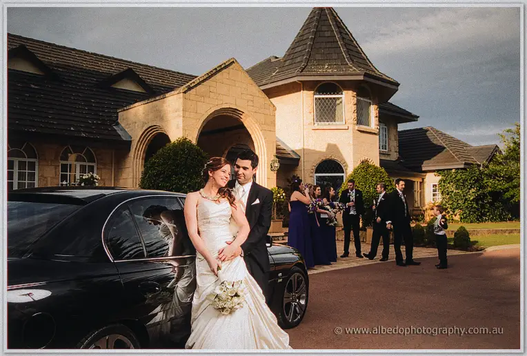 The couple wait by the limousine outside Brookleigh's chateau-style homestead at dusk