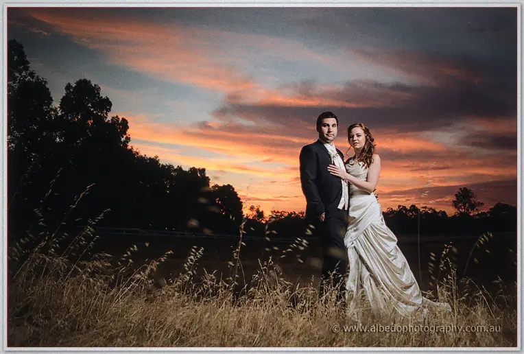 Amanda rests her hand on Craig's chest as they stand tall in the dry grass against a smouldering sunset