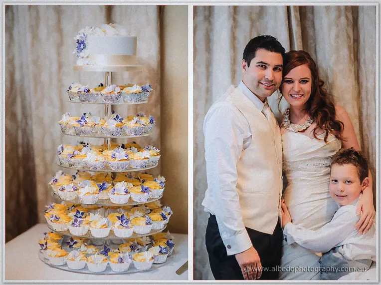 A cupcake tower crowned with a small white cake sits beside the couple's portrait with their page boy