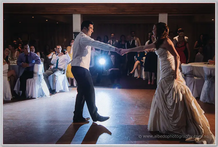 Amanda and Craig swing into their first dance across the reception floor as seated guests watch on