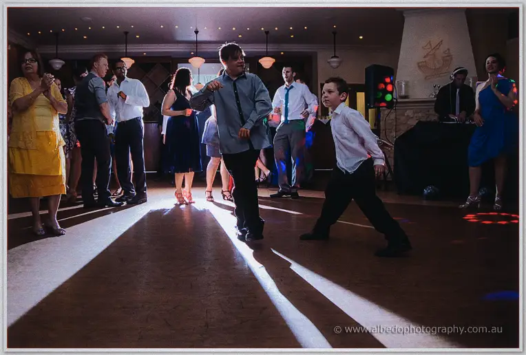 Wide view of the Brookleigh dance floor as guests and two young boys dance under party lights