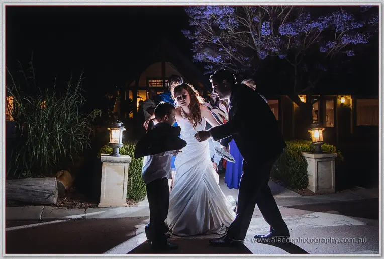 Amanda leads the page boy and groom beneath a flowering jacaranda outside Brookleigh at night