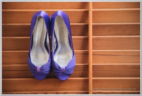 Cayla's purple peep-toe bridal heels rest on warm timber slats in soft natural light