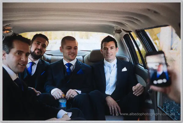 Joe and his groomsmen grin from a limousine's back seat as a phone captures the moment