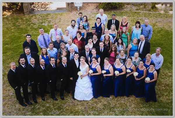 Large wedding group gathered on a lawn with the bride and groom front and centre