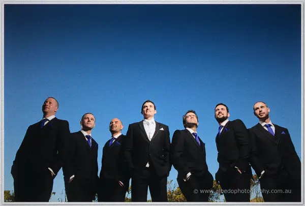 Joe and his groomsmen shot from below against a cloudless cobalt sky