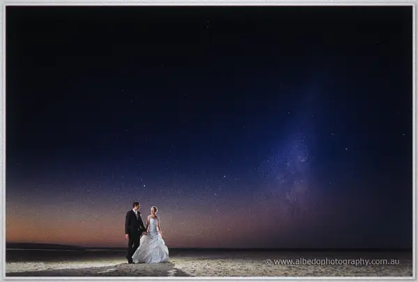 Cayla and Joe stand together on a dark beach beneath a starry Milky Way sky after their Dunsborough wedding