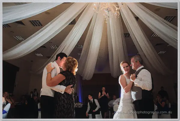 Joe dances with his mother in dark lace as Cayla waltzes with her father under the chandelier canopy