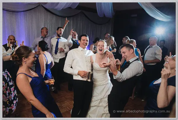 Cayla and Joe sing together with tankard and wine glass amid dancing guests on the crowded floor
