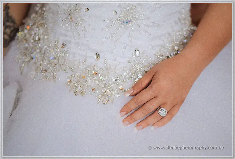 Ringed hand resting on crystal-beaded tulle, the bride's new diamond band taking centre stage