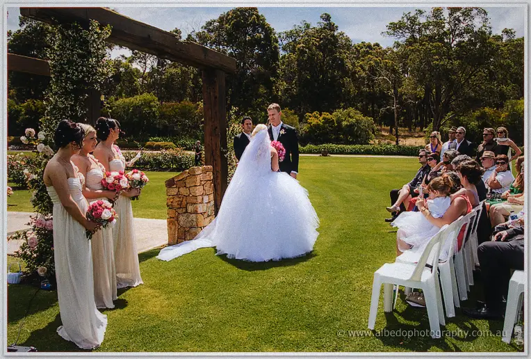 Wide ceremony scene of Steph and Luke at the altar with bridesmaids and seated guests on the lawn.