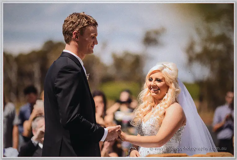 Steph beams up at Luke as they hold hands during their vineyard ceremony.