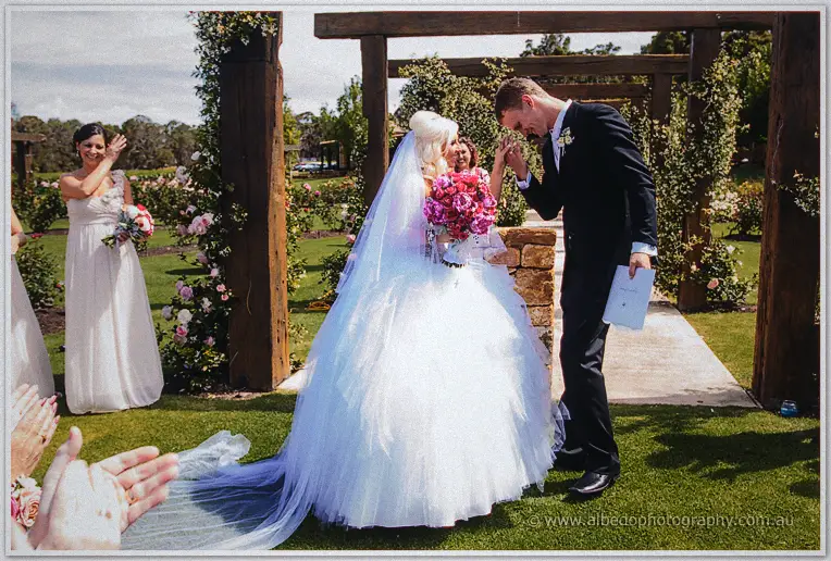 Luke kisses Steph's hand as guests applaud during the recessional under the timber arches.