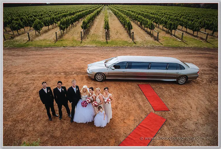 Overhead view of the bridal party by the limousine beside red carpet runners in the vineyard.