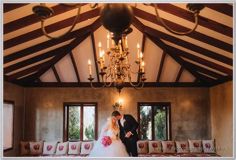 Under the brass chandelier Luke kisses Steph's forehead on the cushioned window seat.