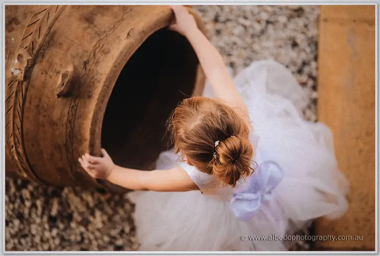 Flower girl leaning over a large terracotta pot on the gravel at Laurance Wines in Margaret River