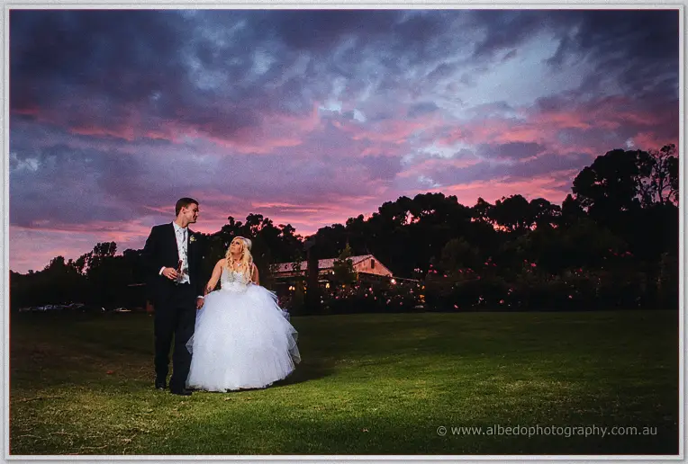 Couple walking the lawn at Laurance Wines beneath a pink and purple sunset sky