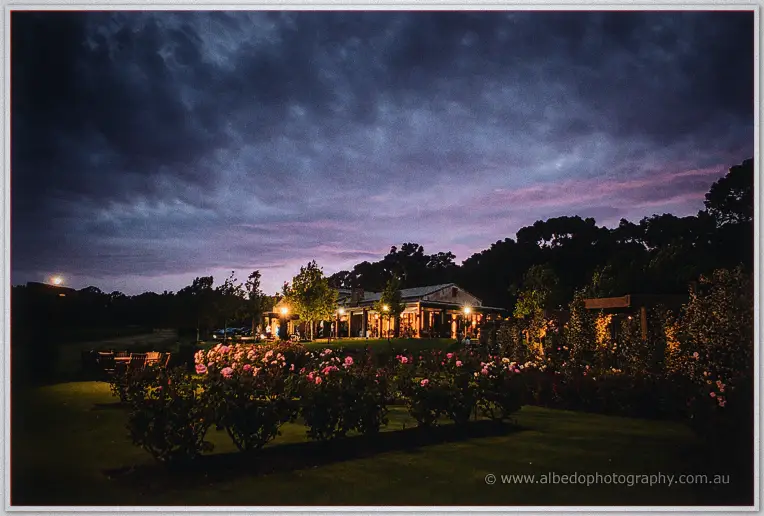 Laurance Wines' barn and rose garden glowing under a stormy purple evening sky