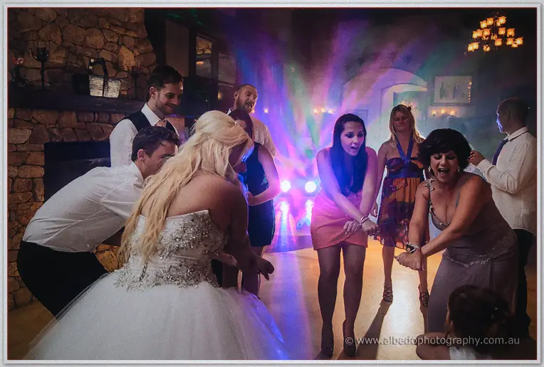 Steph laughing as she dances with guests in a circle under purple party lighting