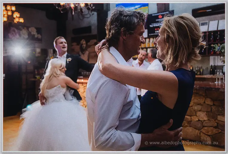 Couple's parents dance and smile in the foreground while the newlyweds sway behind